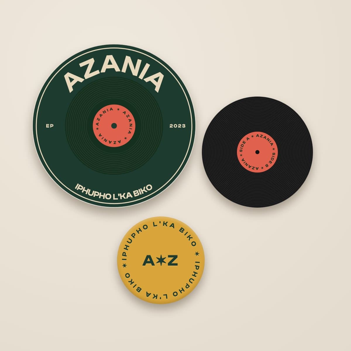 Concept mock-up: three round badges — a green record badge reading Azania, a black vinyl pin with a red label, and a gold badge reading iPhupho L'ka Biko